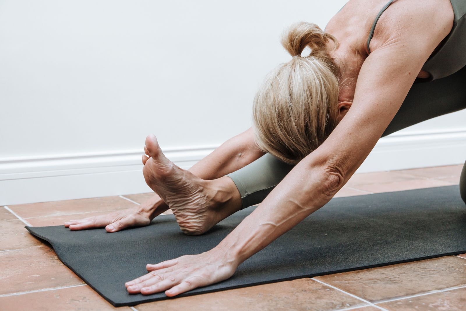 Woman stretching on a yoga mat in a calm indoor setting.